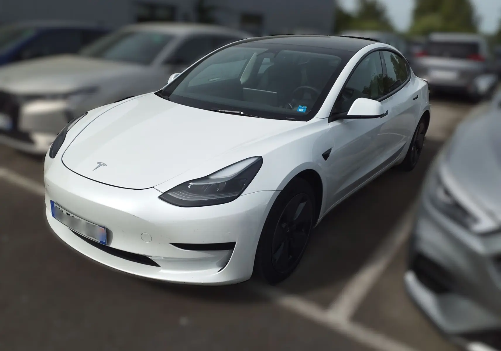 Tesla Model 3 blanc vue 3/4 avant droit, toit panoramique noir et jantes aérodynamiques noires visibles.