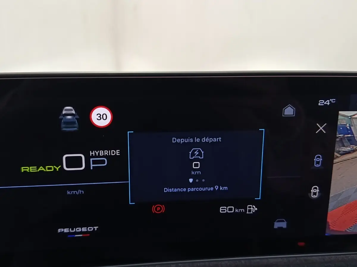 Affichage numérique du tableau de bord Peugeot 5008 hybride rechargeable montrant la vitesse, autonomie et aide au stationnement.