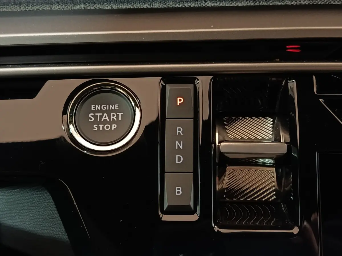 Gros plan sur la console centrale noire brillante du Peugeot 5008 gris clair, avec bouton start/stop et commandes de boîte automatique.