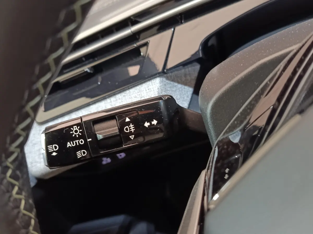 Gros plan sur la commande des phares et clignotants à gauche du volant d’un Peugeot 5008 gris clair 2026.