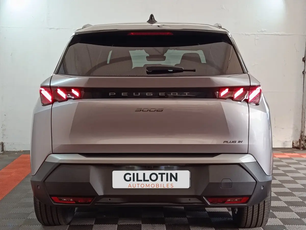 Vue arrière d'un Peugeot 5008 gris clair 2026 avec feux LED allumés et badge Plug-in visible.