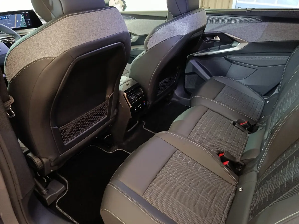 Vue intérieure arrière côté droit du Peugeot 5008 gris clair, montrant les sièges et la console centrale avec commandes climatisation.