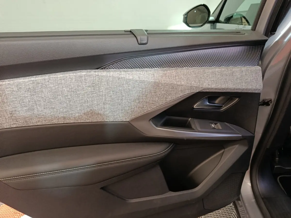 Vue rapprochée de la porte avant droite du Peugeot 5008 gris clair, avec habillage tissu clair et garnitures noires.