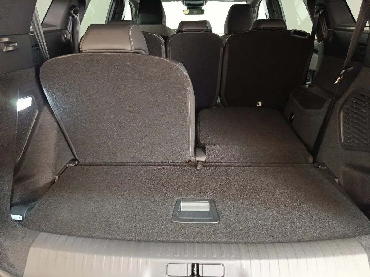 Vue arrière du coffre du Peugeot 5008 gris clair avec sièges rabattus partiellement pour agrandir l'espace de chargement.