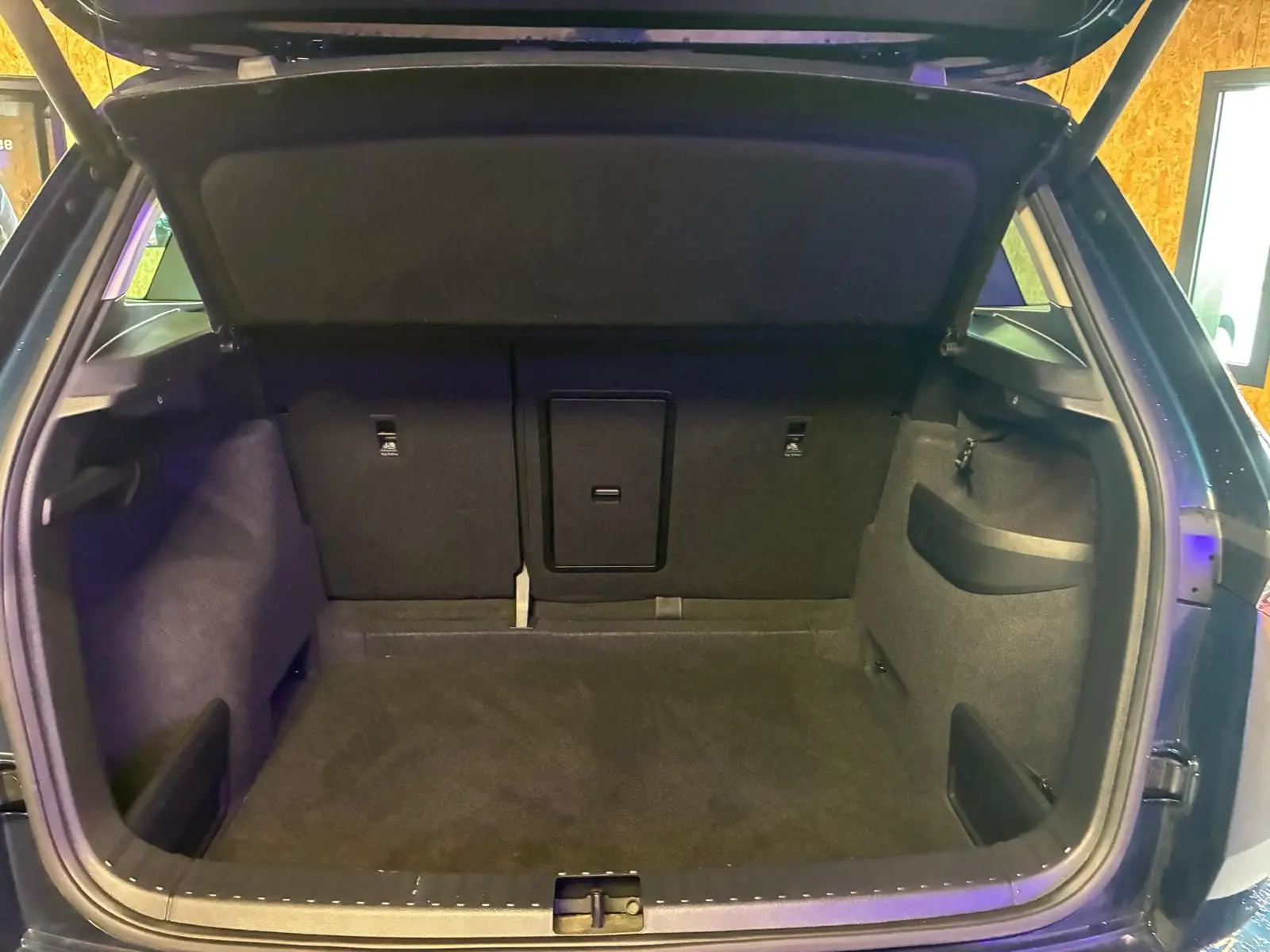 Coffre ouvert vu de l'arrière d'un Skoda Karoq bleu 2023, montrant l'espace de chargement et les rangements latéraux.