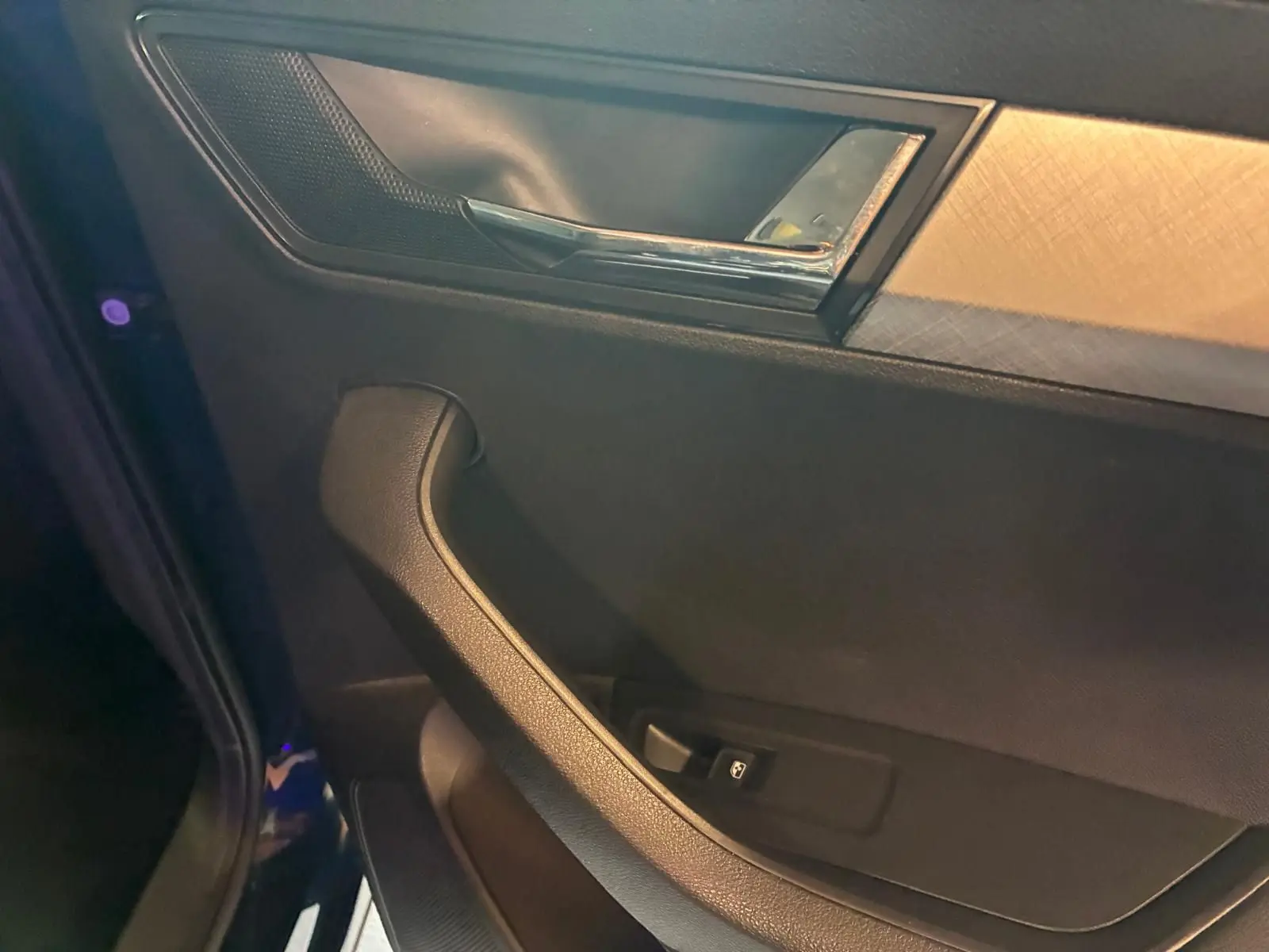 Détail de la porte intérieure côté gauche d'une Skoda Karoq bleu 2023 avec poignée noire et insert décoratif gris.