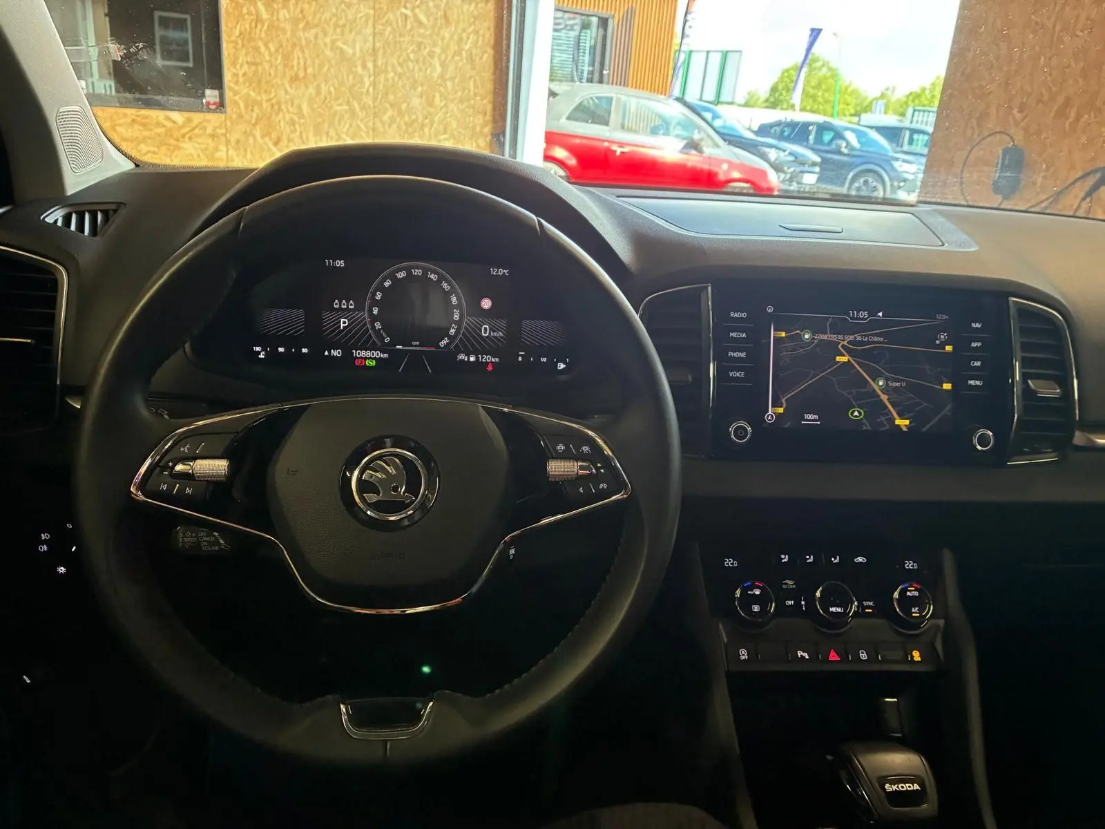Vue intérieure centrée sur le volant multifonctions et le tableau de bord numérique d'une Skoda Karoq 2023, avec écran tactile de navigation.