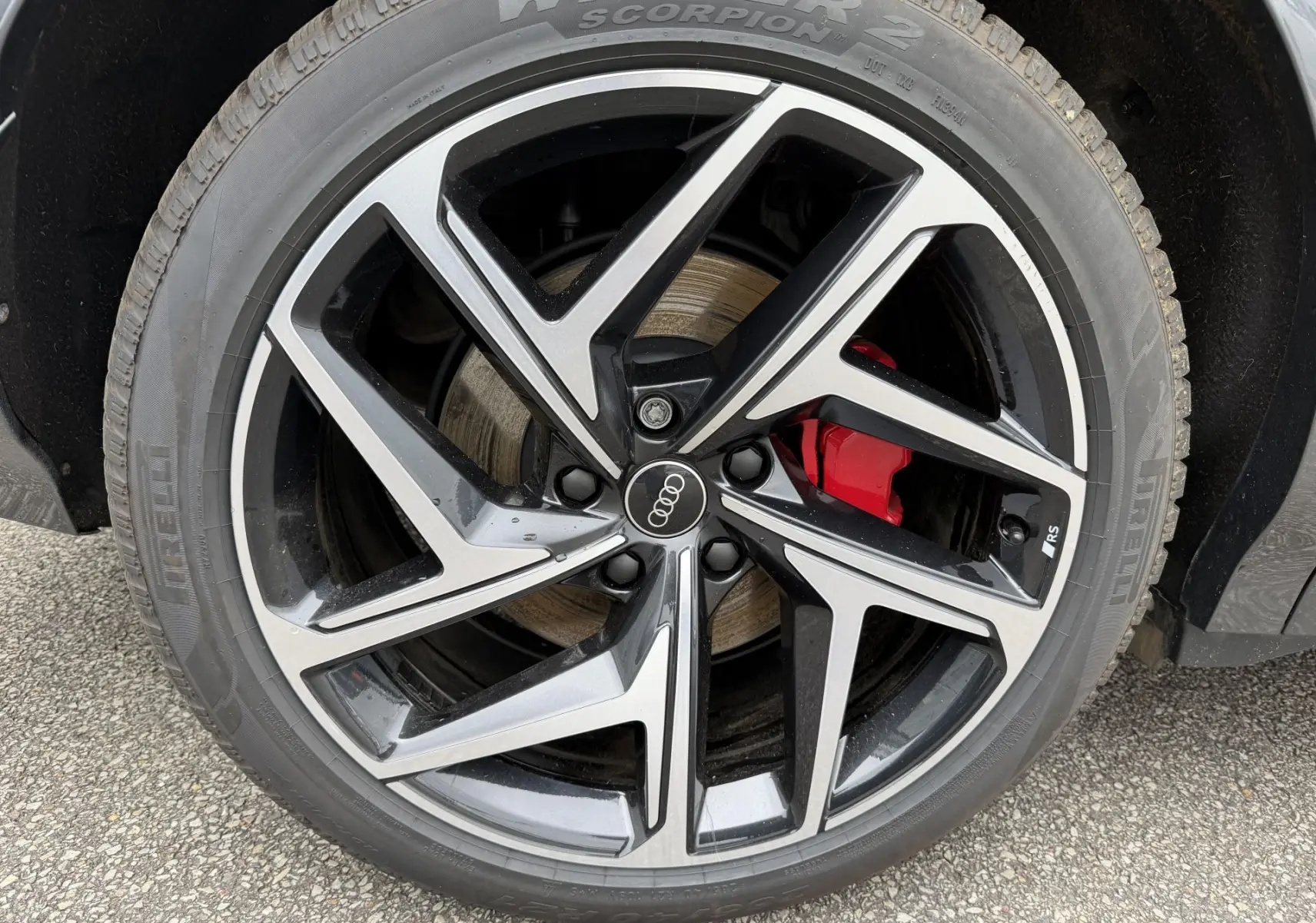 Gros plan sur la jante Audi Sport noire métallisée à 5 branches en Y avec étrier de frein rouge du Q6 e-tron gris nacré.
