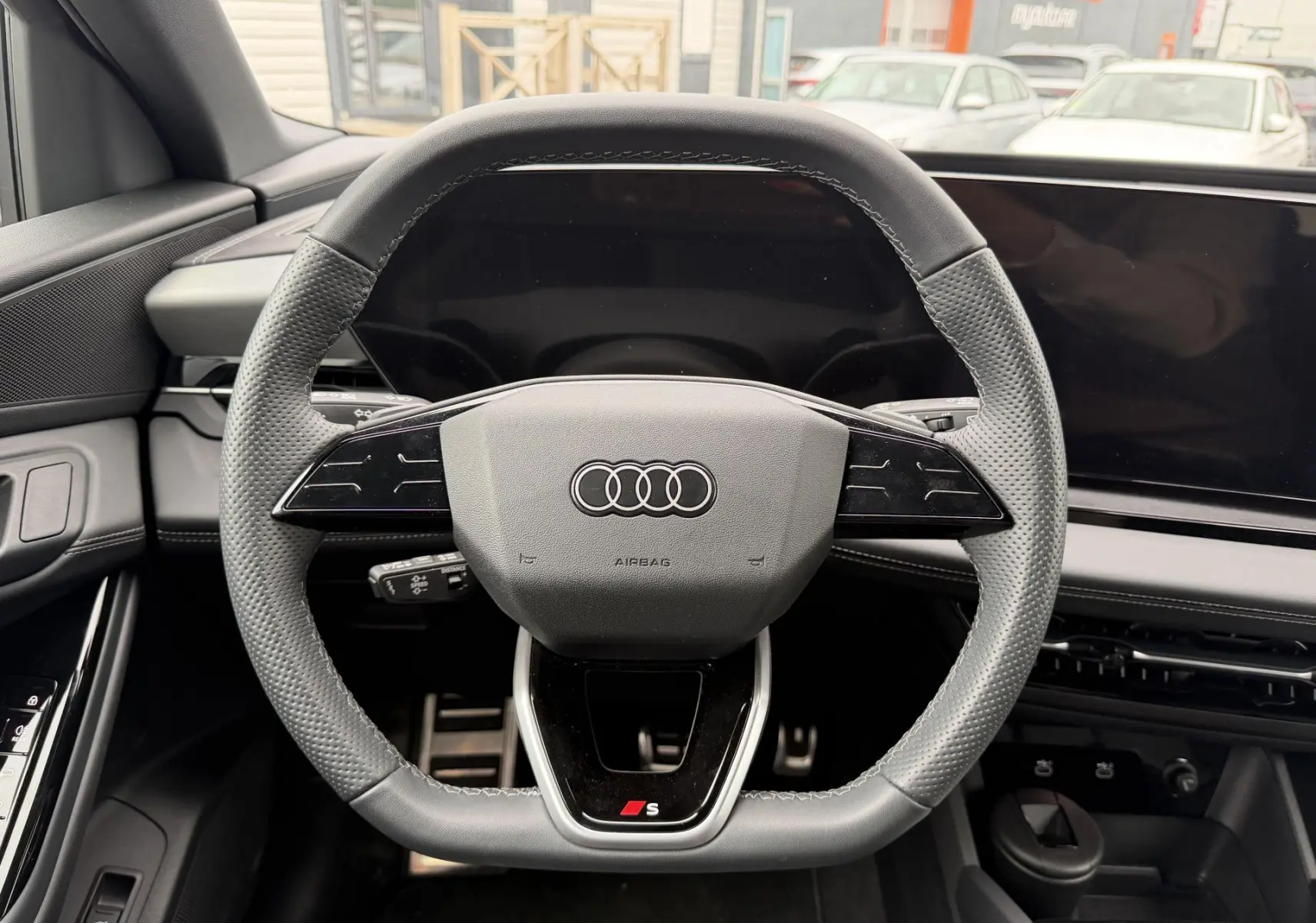 Volant sport multifonction en cuir gris avec logo S, vue frontale de l'habitacle de l'Audi Q6 e-tron 2024.