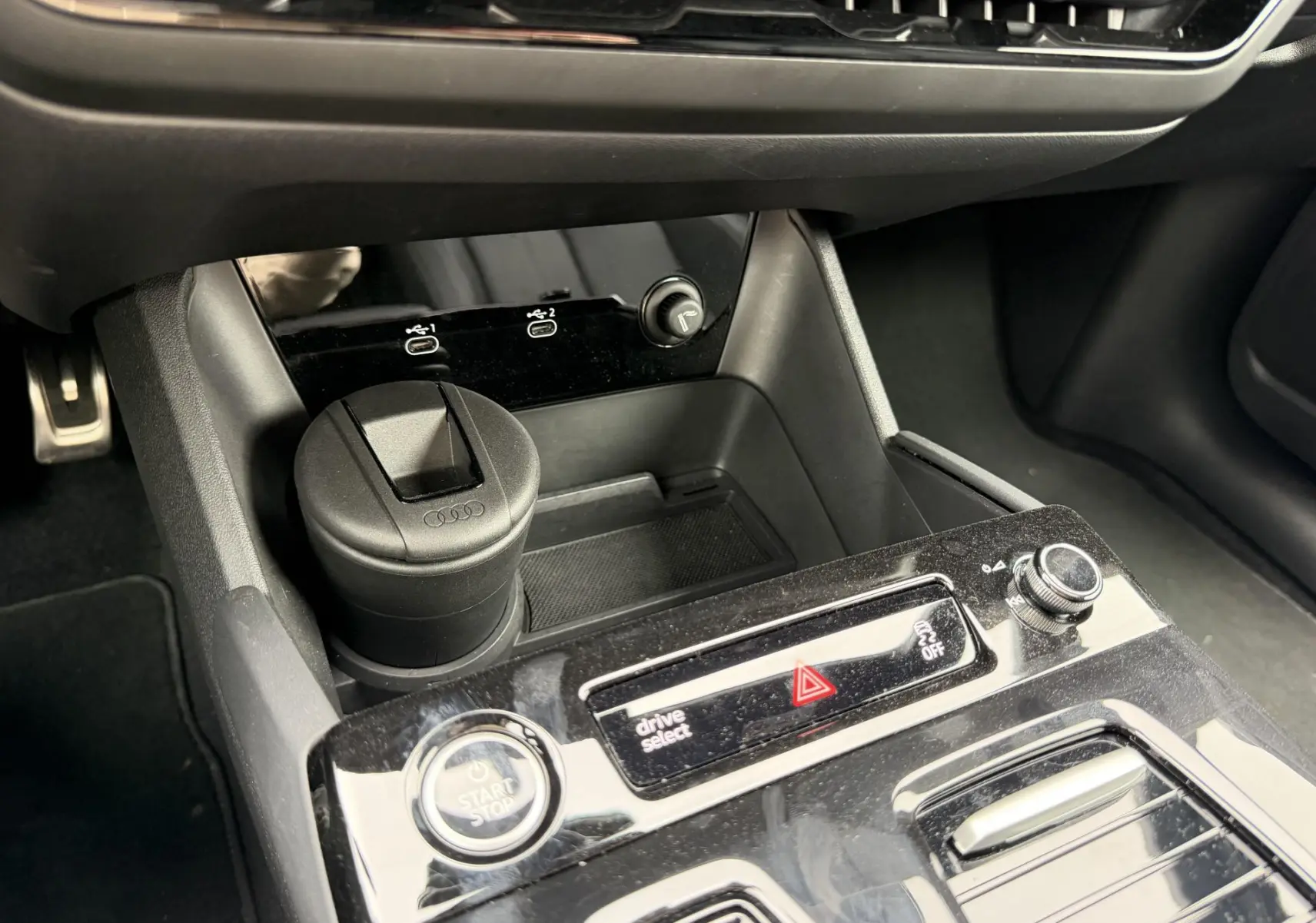 Gros plan sur la console centrale noire brillante de l’Audi Q6 e-tron 2024 avec bouton start/stop et commandes drive select.
