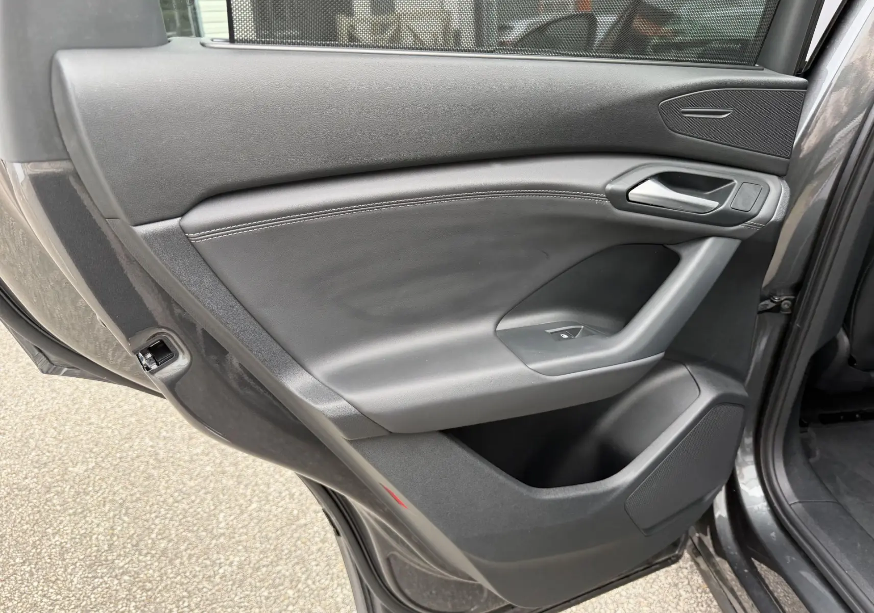 Vue rapprochée de la porte arrière gauche grise nacrée de l'Audi Q6 e-tron avec garniture noire et poignée intégrée.