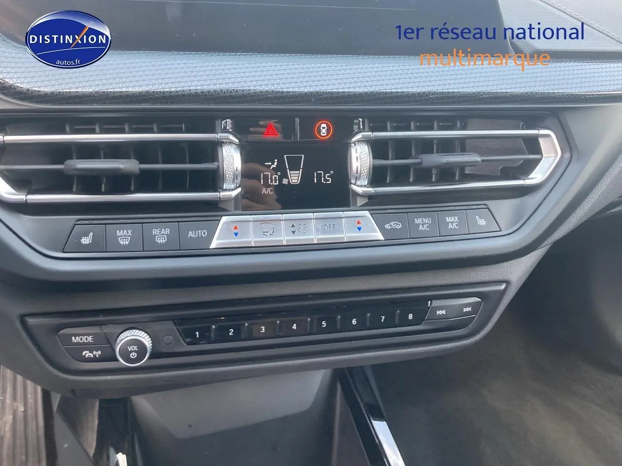 Vue rapprochée de la console centrale de la BMW Série 1 gris foncé avec commandes clim et audio visibles.