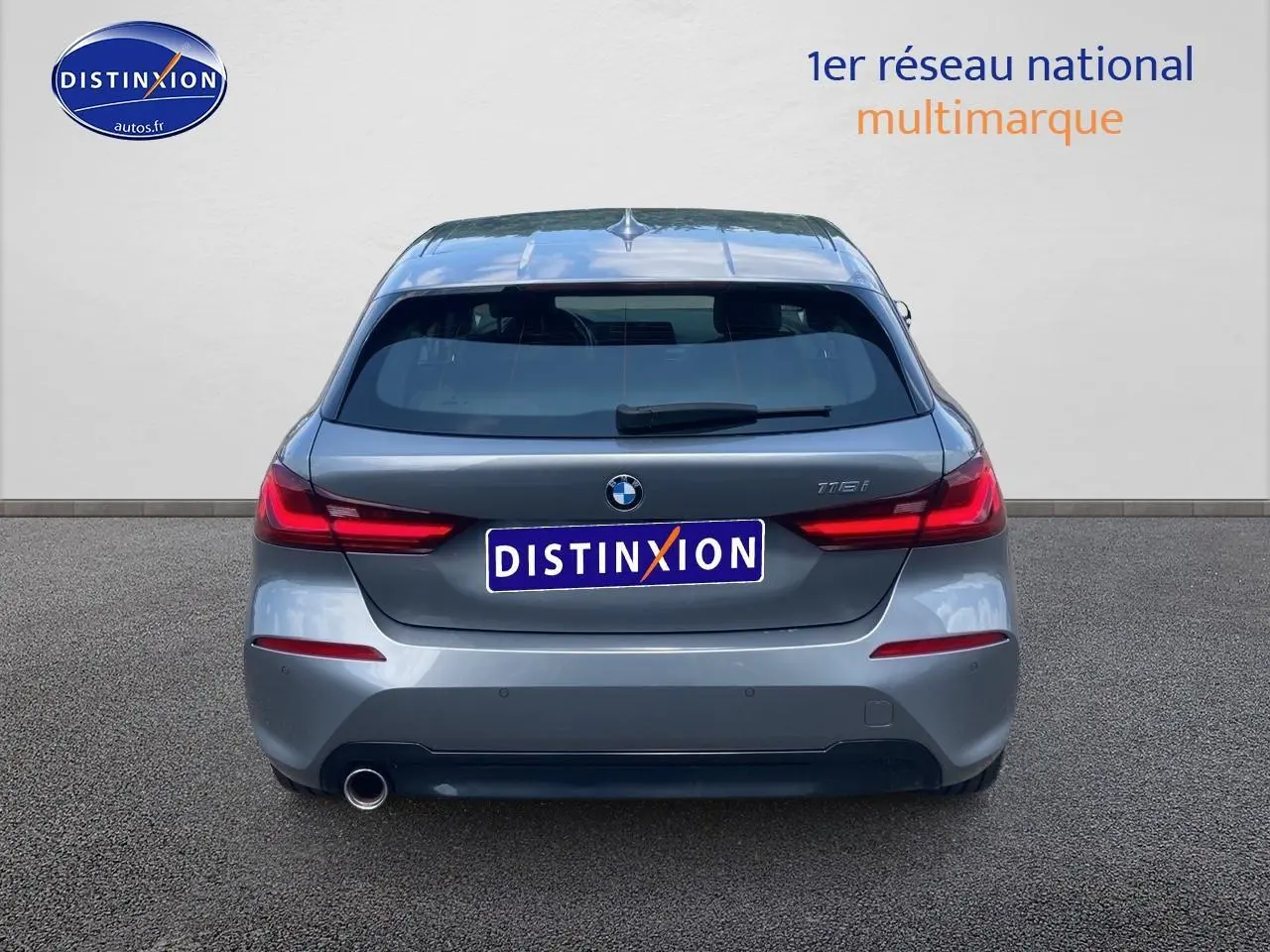 Vue arrière d'une BMW Série 1 118i gris foncé avec feux LED et sortie d'échappement visible sur la gauche.