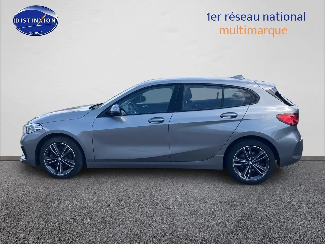 BMW Série 1 gris foncé vue de profil côté gauche, avec jantes alliage 17 pouces et lignes sportives marquées.