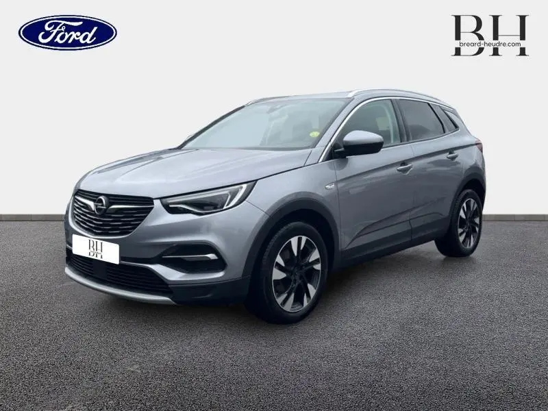 Opel Grandland X gris Quartz vu en 3/4 avant droit avec toit et rétroviseurs noirs sur fond neutre.