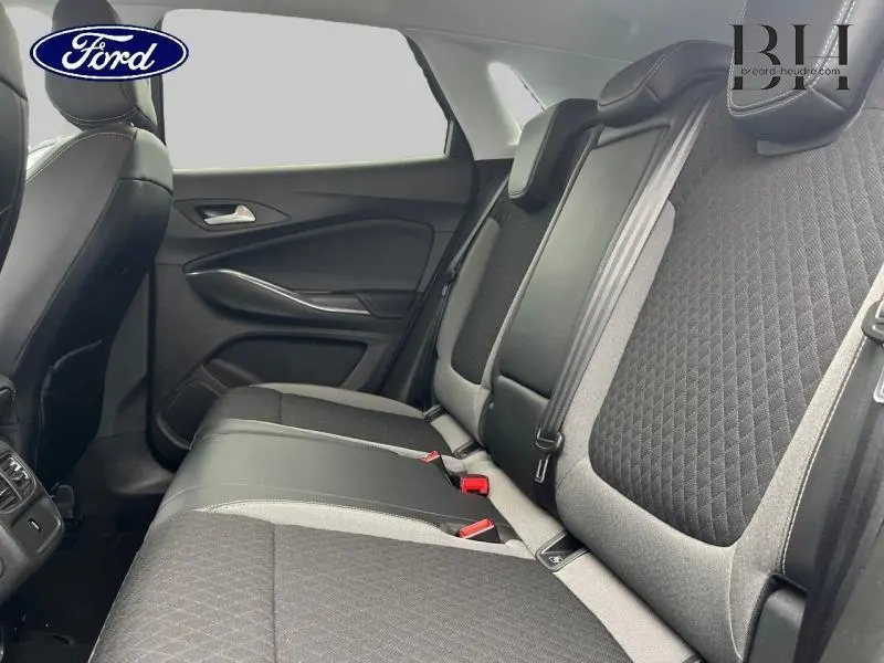 Vue latérale intérieure des sièges arrière gris et noirs de l'Opel Grandland X 2020 avec accoudoir central relevé.