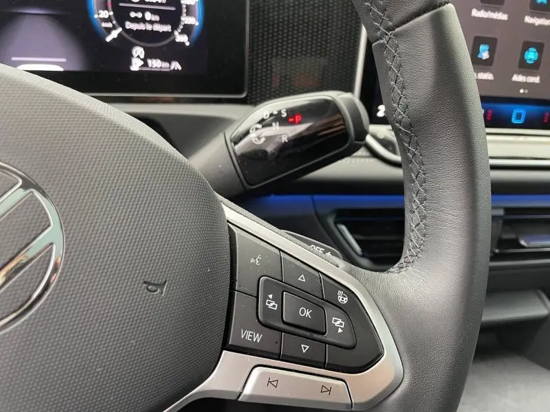 Gros plan sur le volant cuir noir du Volkswagen Tiguan 2025 avec commandes multifonctions et levier de boîte auto visible.