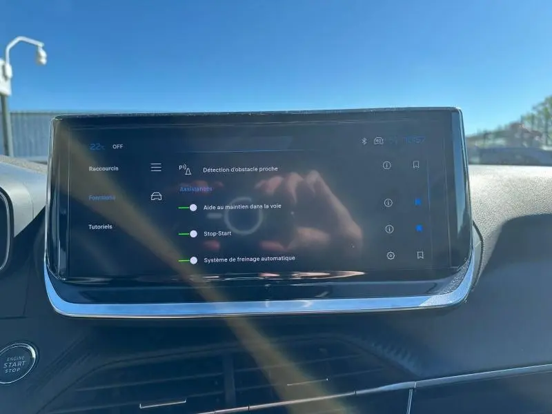Écran tactile central du tableau de bord du Peugeot 2008 2025 affichant les aides à la conduite, avec reflet du photographe.