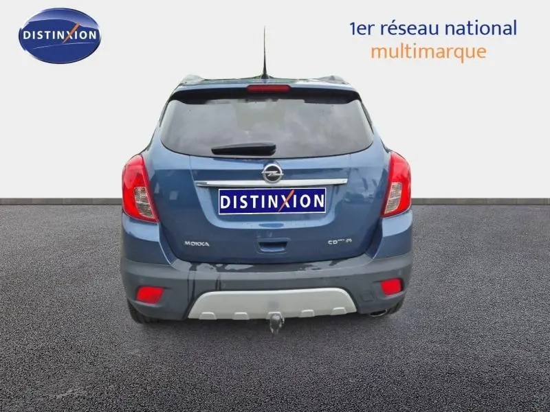 Vue arrière d'un Opel Mokka bleu outremer avec hayon teinté et attelage de remorque visible.