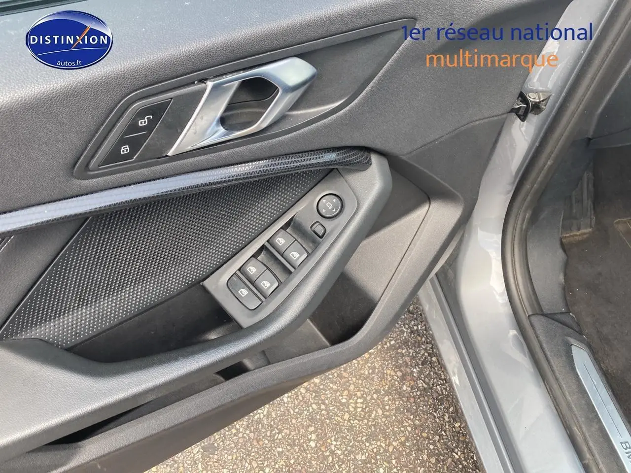Détail de la porte avant gauche grise d'une BMW Série 1 118i 2023 avec commandes des vitres et serrure intégrée.