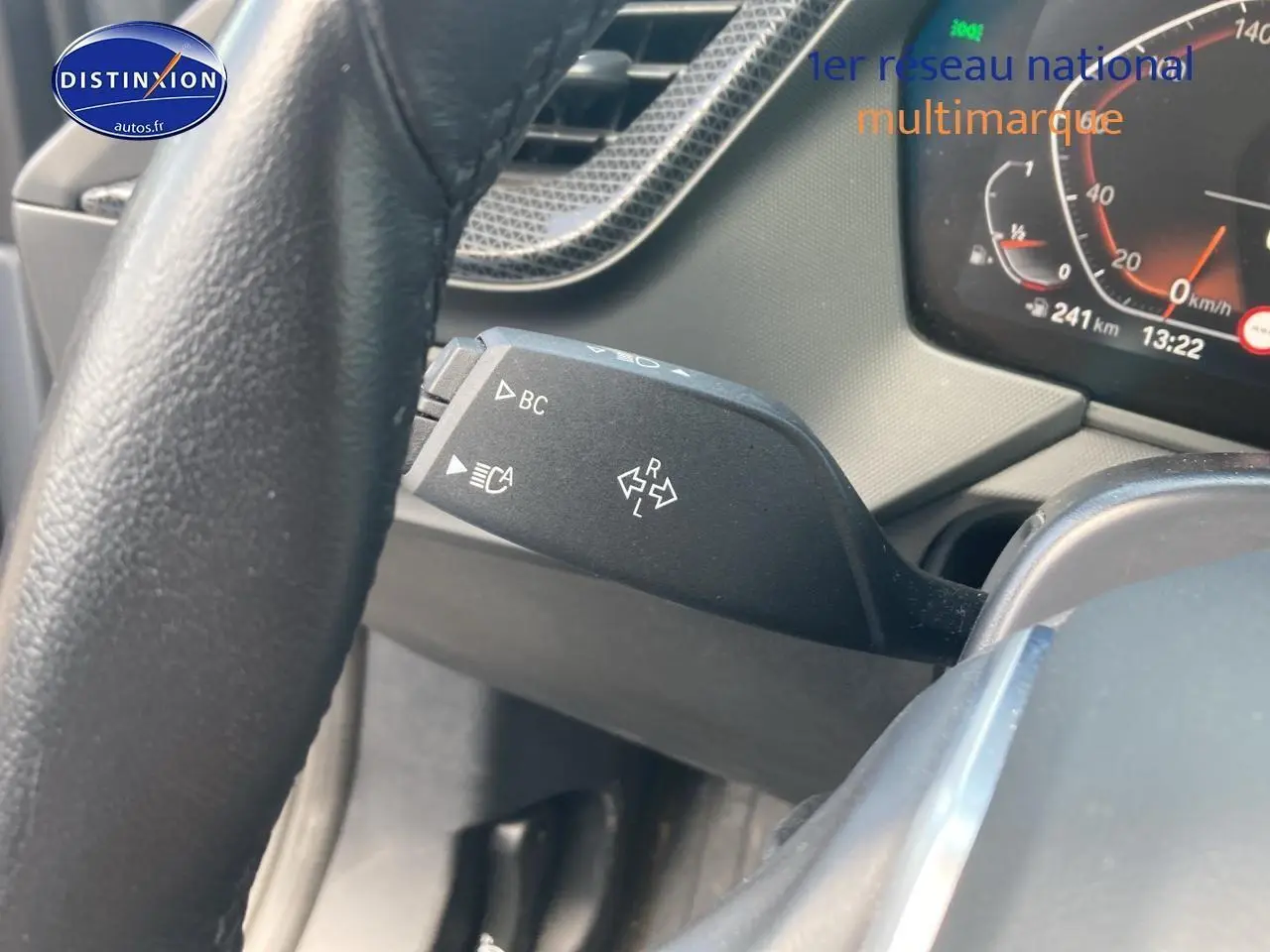 Gros plan sur la commande de clignotant à gauche du volant d'une BMW Série 1 118i 2023, tableau de bord visible.