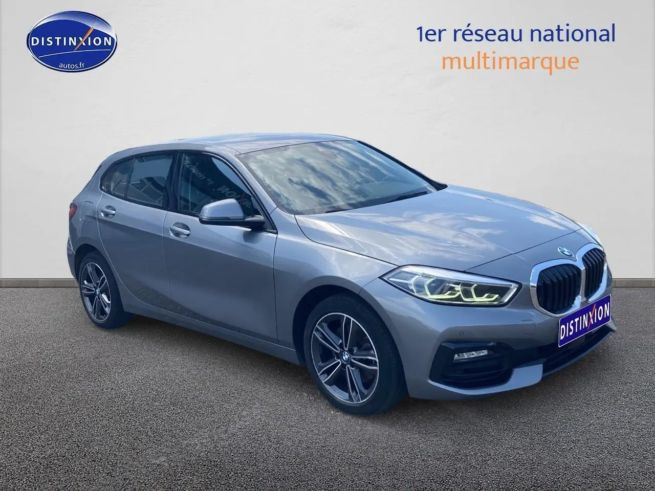 BMW Série 1 gris foncé vue 3/4 avant droit avec phares LED allumés et jantes alliage 17 pouces style 549