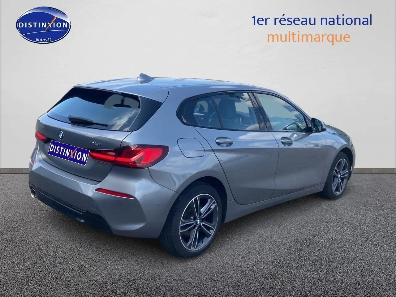 Vue 3/4 arrière droite d'une BMW Série 1 gris foncé avec jantes alliage et feux LED distinctifs.