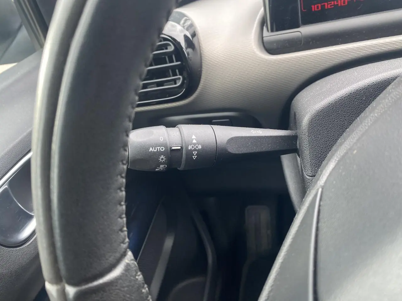 Gros plan sur la manette de commande d'éclairage à gauche du volant d'une Citroën C4 Cactus blanche.