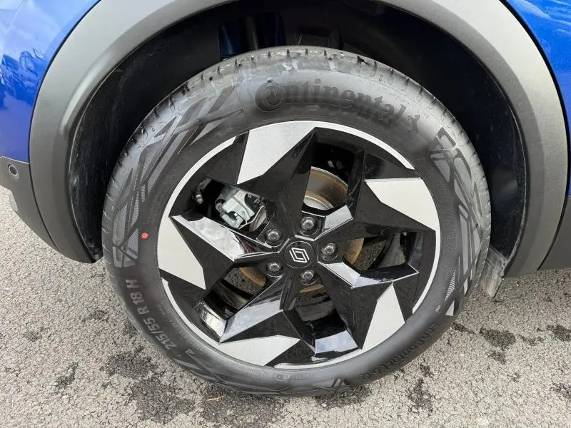 Gros plan sur la roue avant gauche du Renault Captur 2025 Bleu Iron/Noir Étoilé avec jante noire à motifs géométriques.