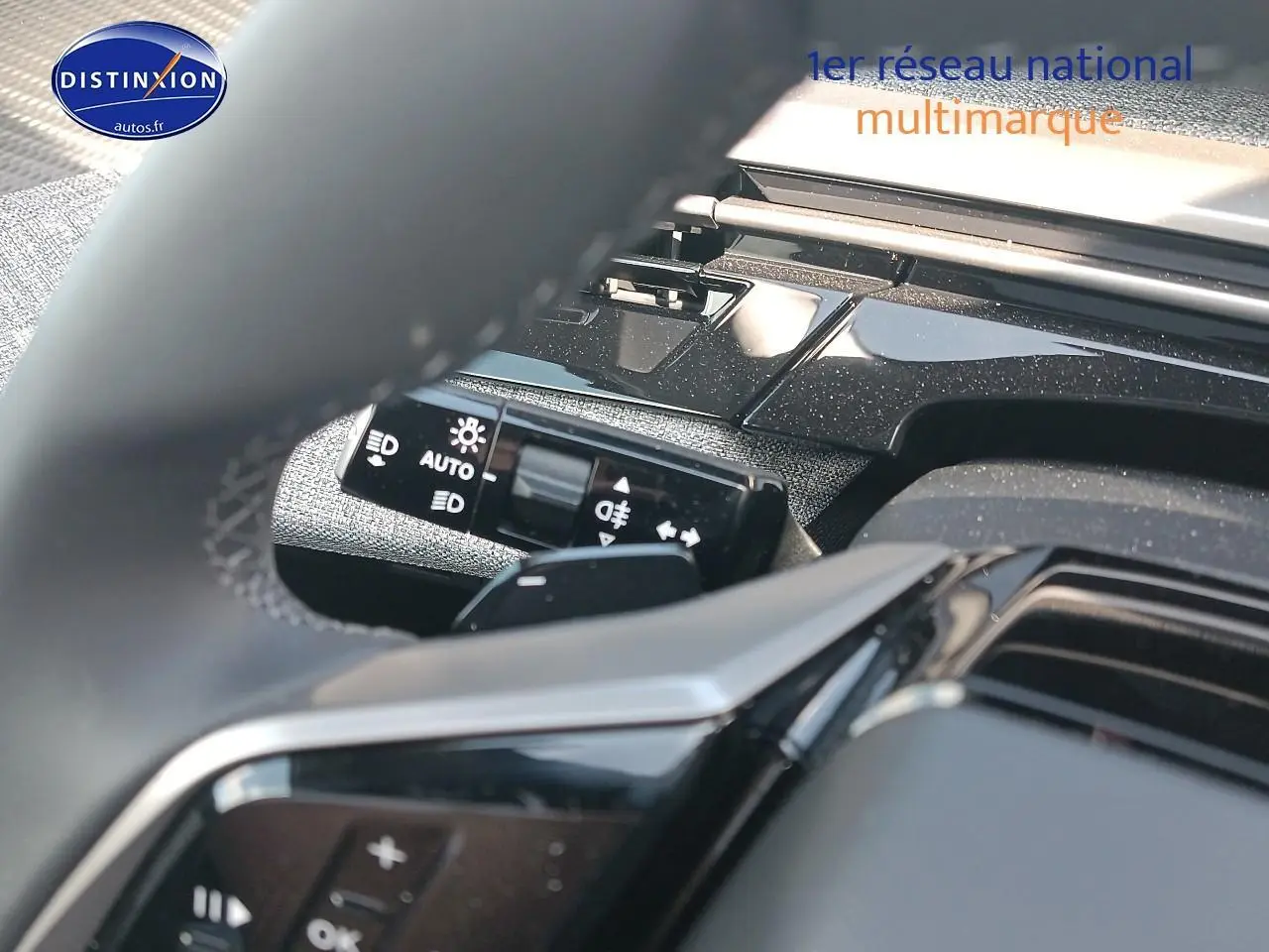 Détail du commodo d'éclairage et partie du volant noir dans l'habitacle d'un Peugeot 3008 bleu 2025.