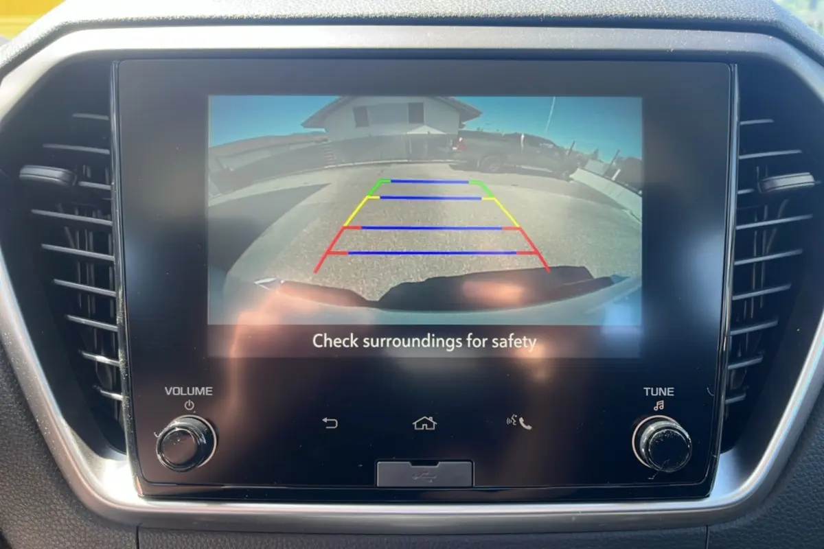 Écran tactile intérieur montrant la caméra de recul du pick-up Isuzu D-MAX blanc, vue arrière avec lignes de guidage colorées.
