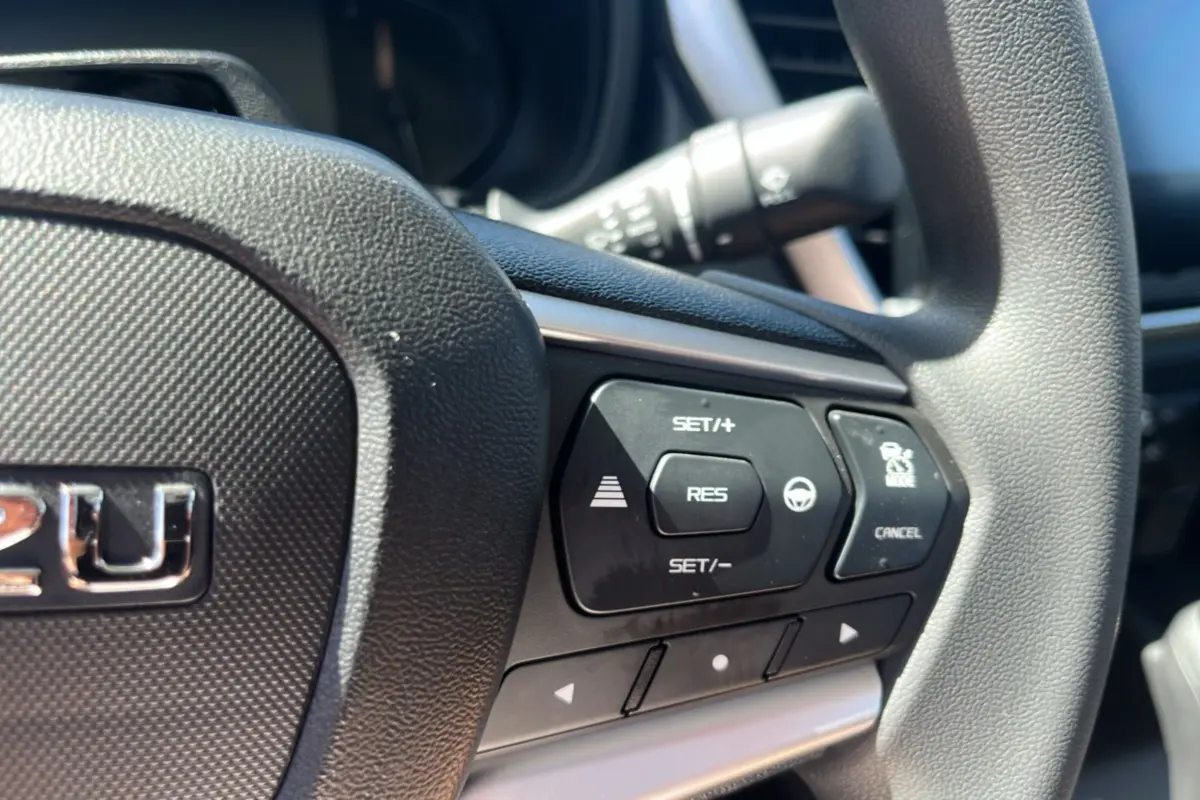 Gros plan sur le volant multifonctions noir de l'Isuzu D-MAX 2026 avec commandes de régulateur et assistance.