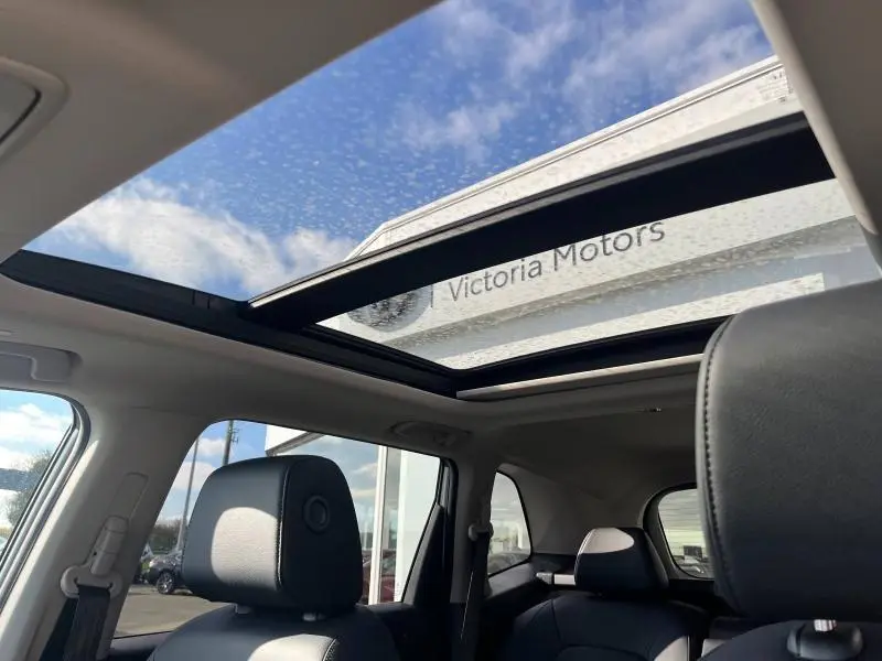 Vue intérieure du toit panoramique ouvert du Honda CR-V 2024 avec sièges cuir noir et ciel bleu visible à travers le verre.