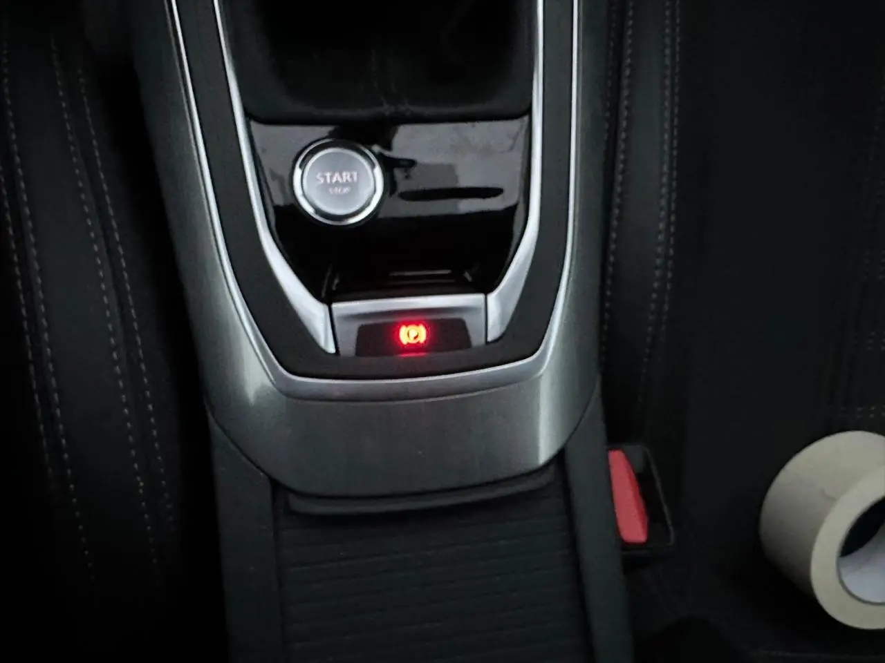 Gros plan sur la console centrale de la Peugeot 308 2018, bouton start et frein de parking électrique allumé.