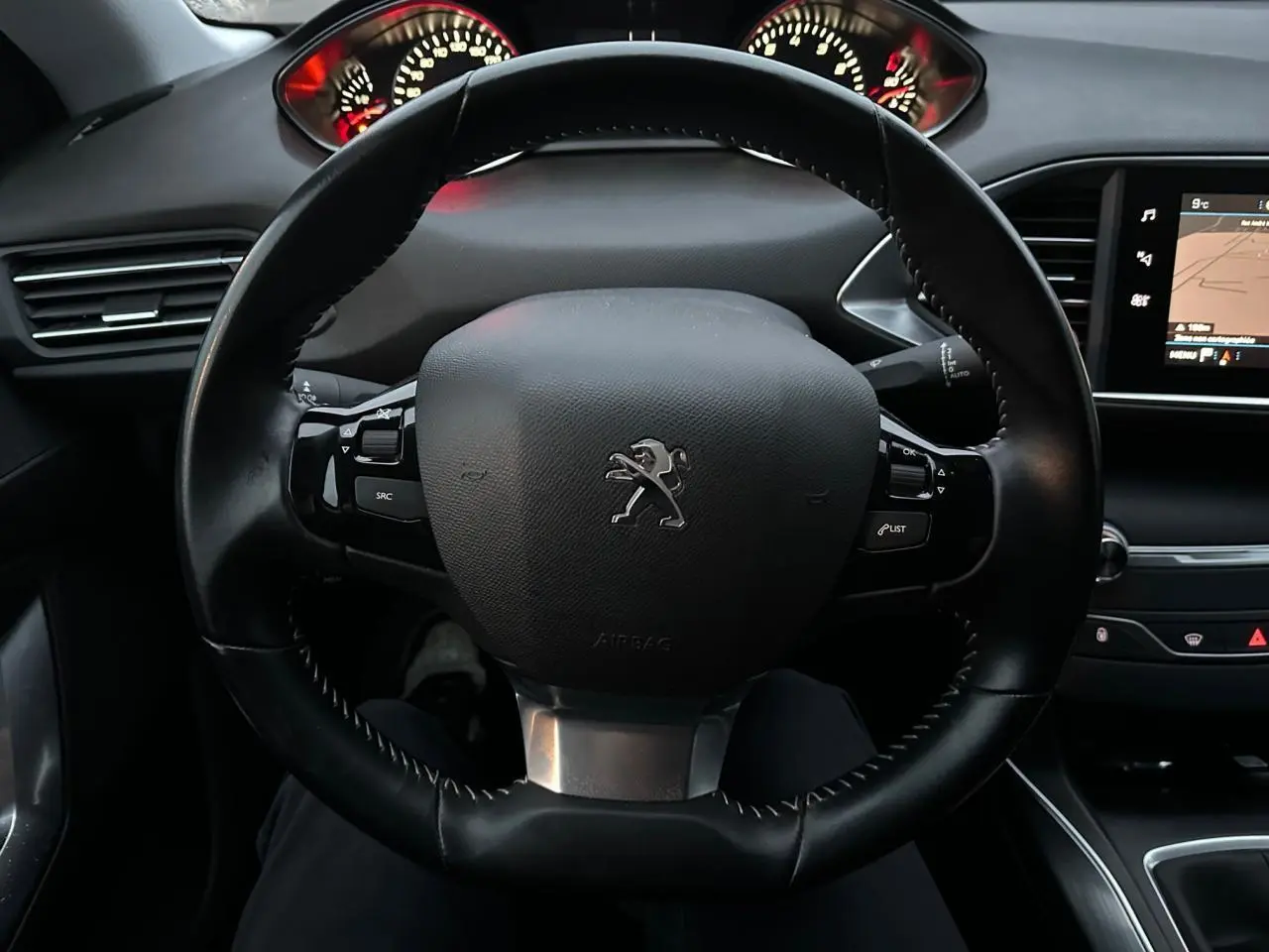 Vue rapprochée du volant noir de la Peugeot 308 2018 avec tableau de bord et écran tactile visible à droite.