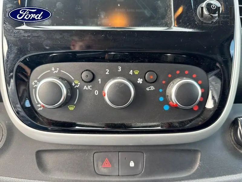 Gros plan sur les commandes de climatisation noires du Renault Trafic Fourgon blanc Glacier de 2019.