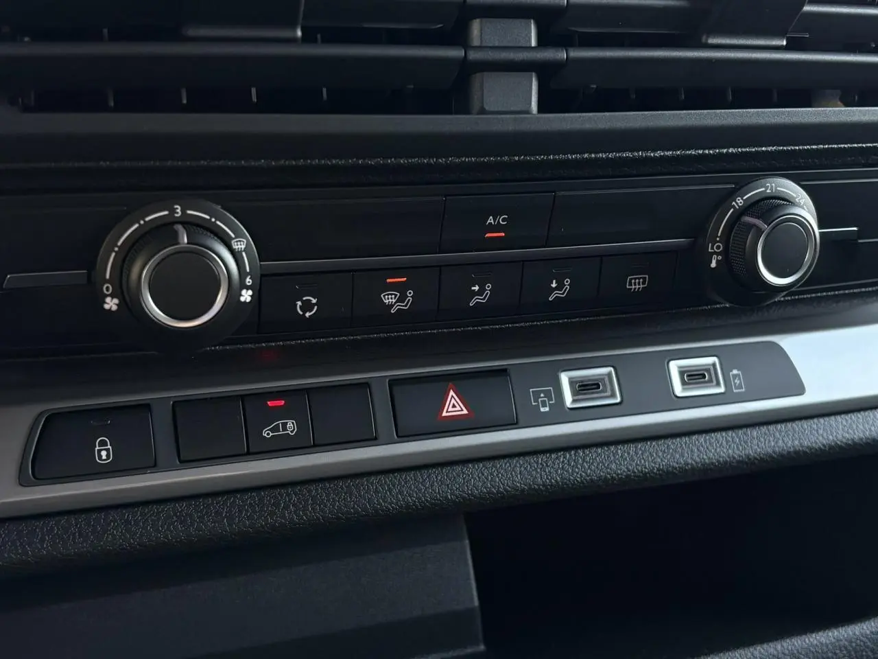 Vue rapprochée du tableau de bord du Citroën Jumpy gris, montrant les commandes de climatisation et boutons centraux.