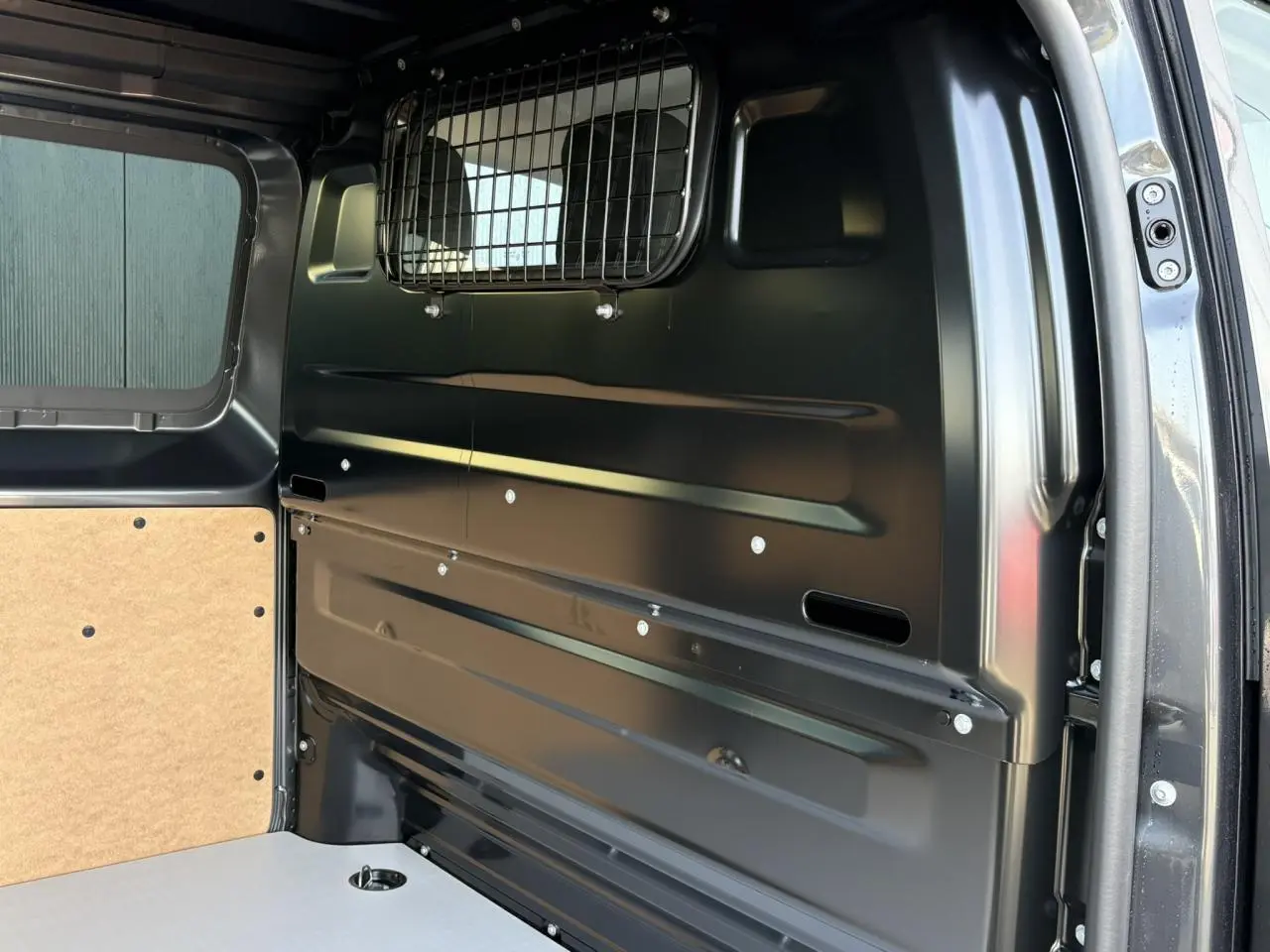 Vue intérieure arrière droite du Citroën Jumpy gris titane, montrant la cloison pleine vitrée et le plancher bois.