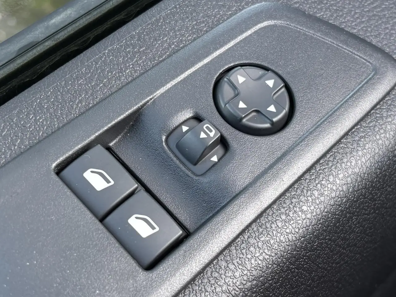 Gros plan sur les commandes de réglage des rétroviseurs et des vitres côté conducteur du Citroën Jumpy gris titane.