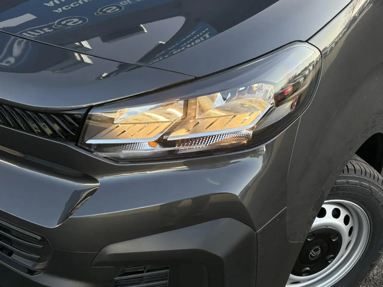 Gros plan sur l’avant droit gris titane du Citroën Jumpy 2025, mettant en valeur le phare allumé et la roue acier.