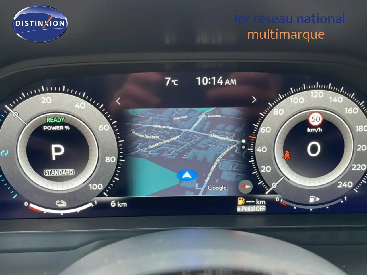 Tableau de bord numérique du Nissan Qashqai blanc nacré, affichant la navigation et les compteurs à 10h14, 7°C.