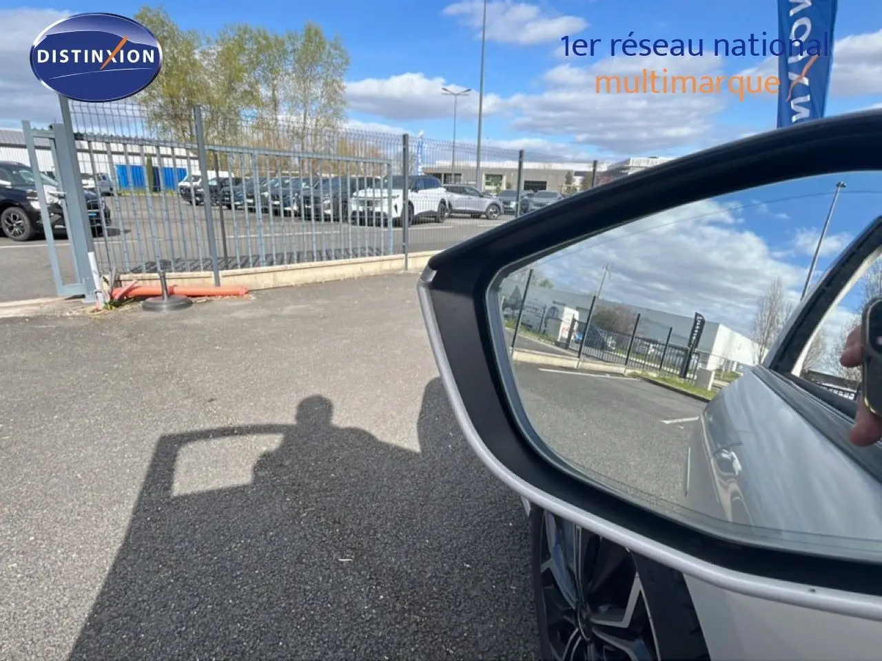 Rétroviseur côté droit reflétant la carrosserie blanche nacrée d'une DS4 2024, avec une roue alliage visible.