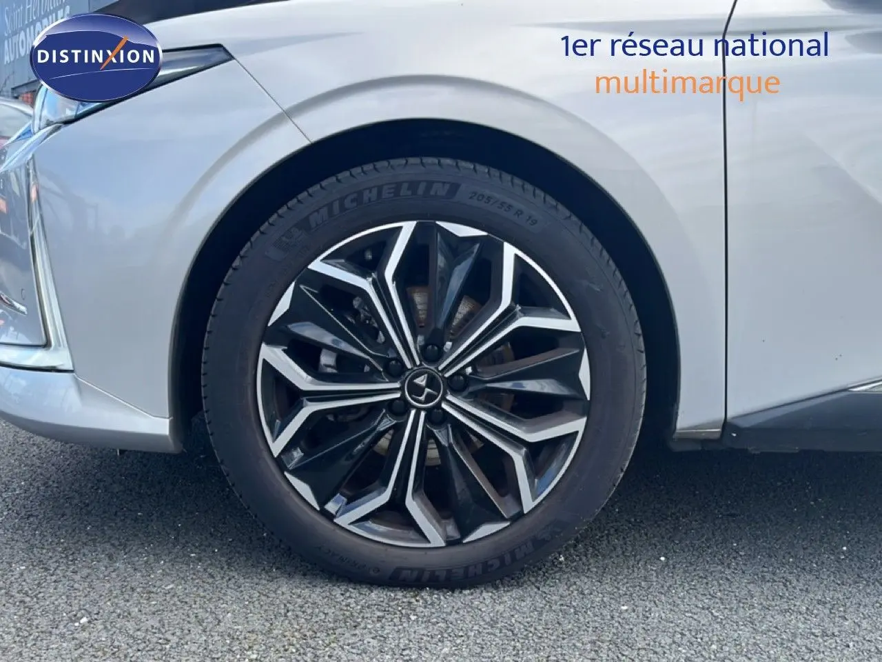 Gros plan sur la roue avant gauche d'une DS4 2024 Cristal Pearl Nacré avec jante alliage noire et argentée.