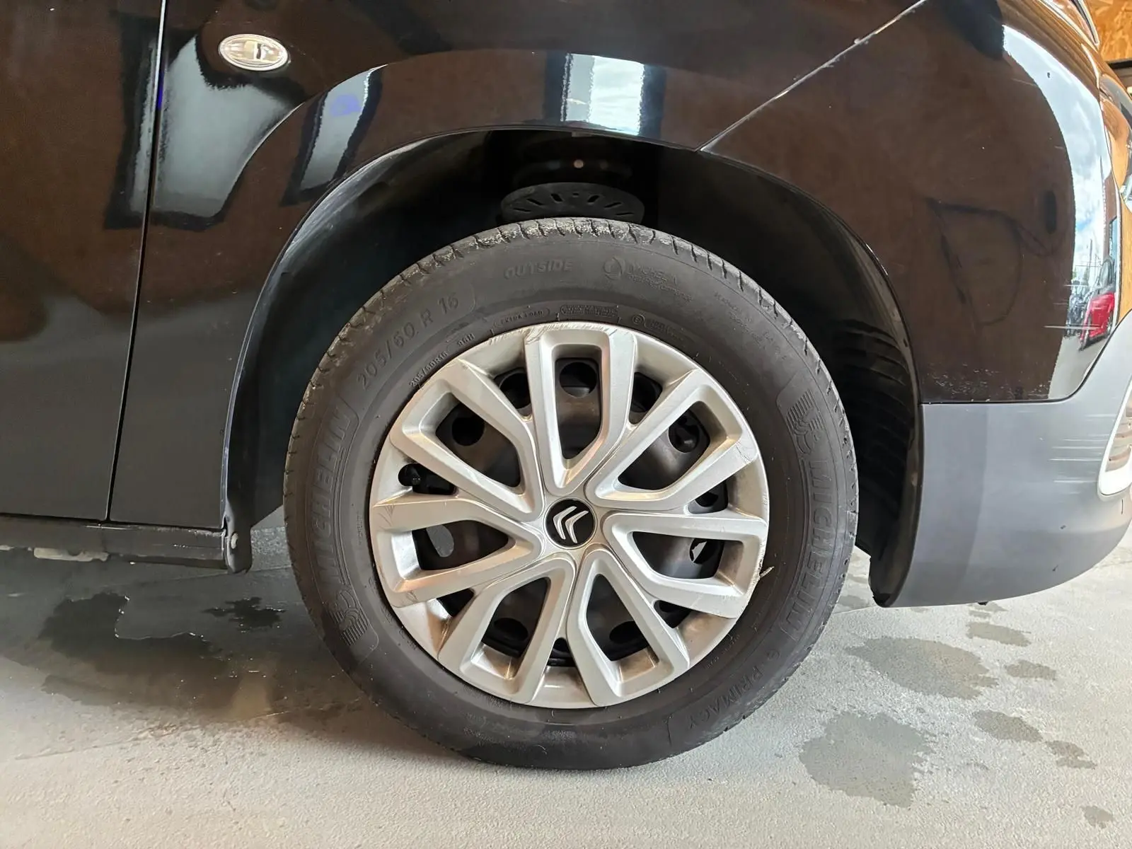 Gros plan sur la roue avant gauche d’un Citroën Berlingo noir 2020 avec jante en alliage et logo Citroën au centre.