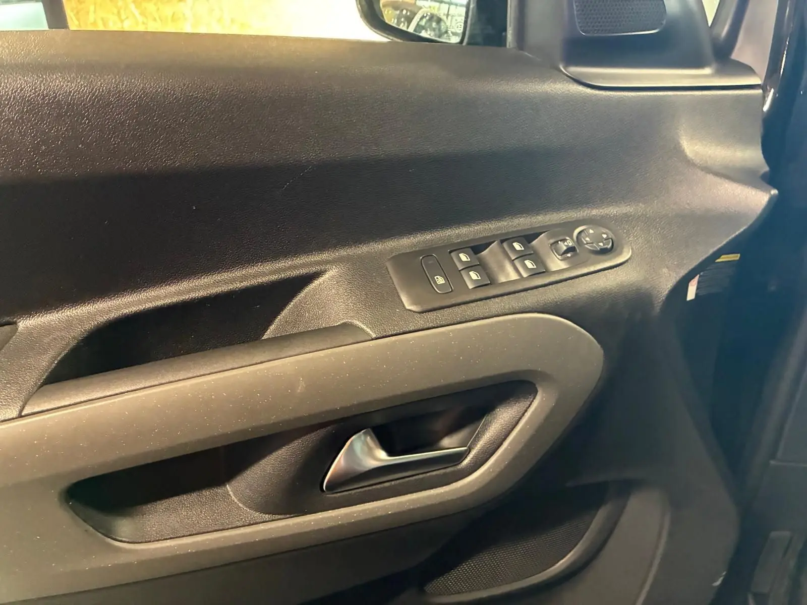 Vue rapprochée de la porte avant gauche noire du Citroën Berlingo 2020, avec commandes électriques et poignée intégrée.