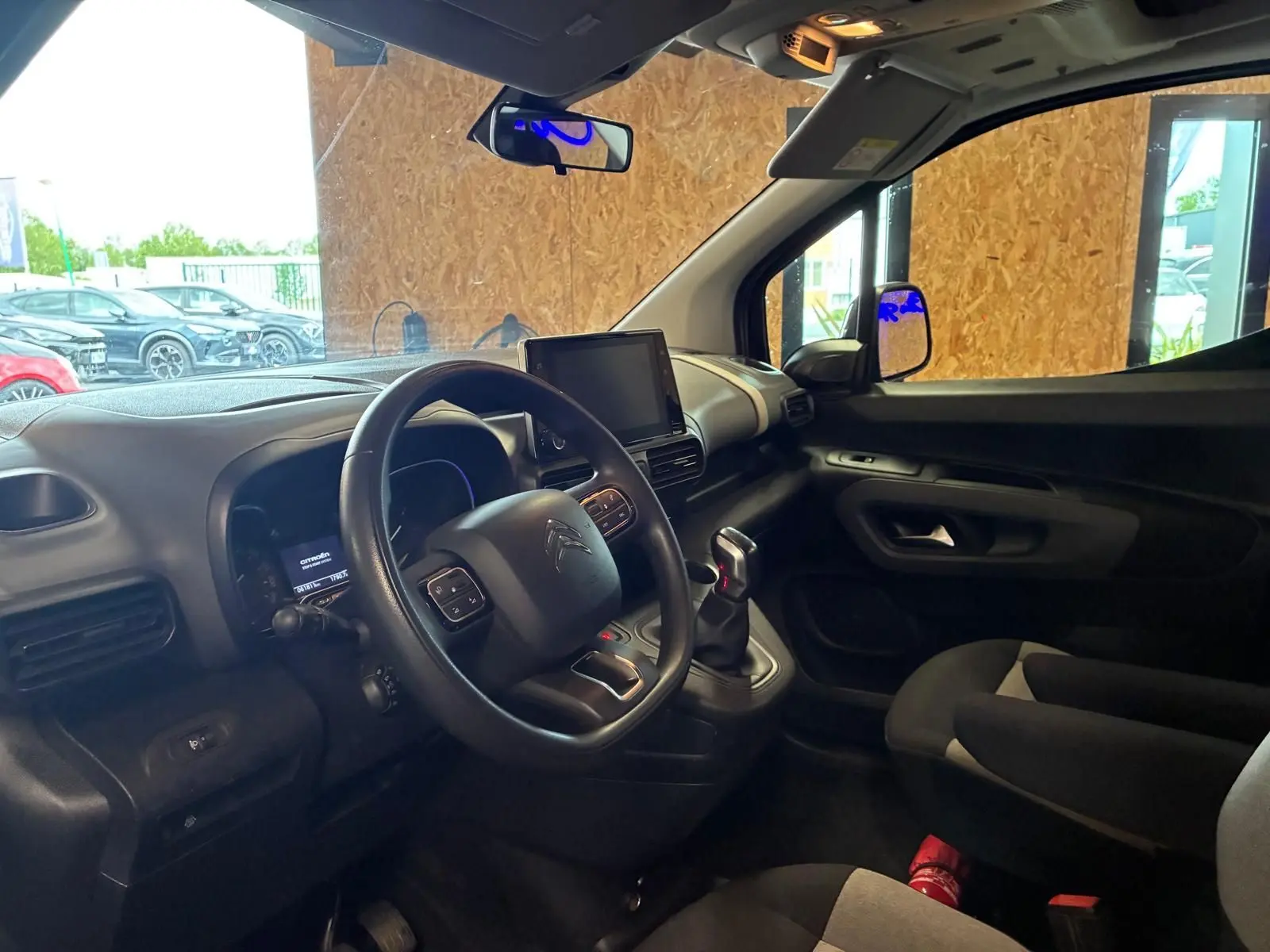 Vue intérieure côté conducteur du Citroën Berlingo noir 2020, montrant le tableau de bord et la console centrale avec écran tactile.