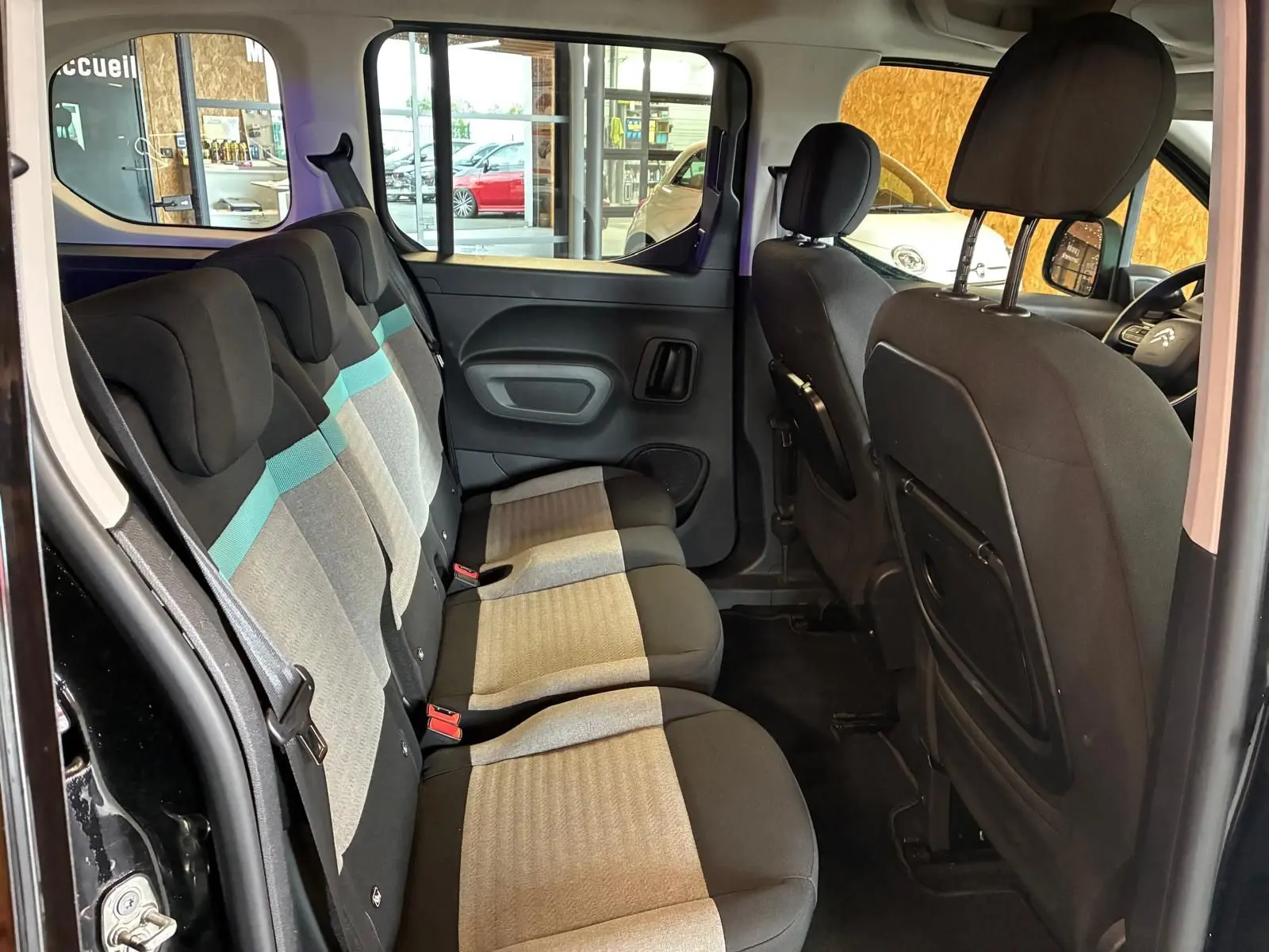Vue intérieure côté gauche montrant la banquette arrière tissu gris et noir avec bande bleue du Citroën Berlingo noir 2020.