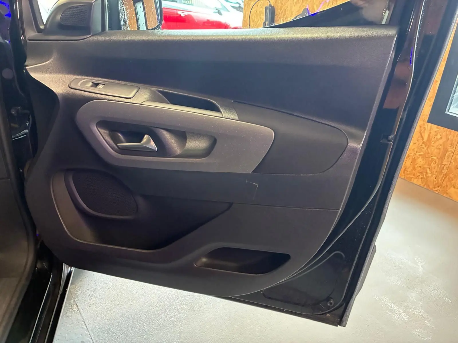 Vue intérieure de la porte avant gauche noire du Citroën Berlingo 2020, montrant la poignée et les commandes.