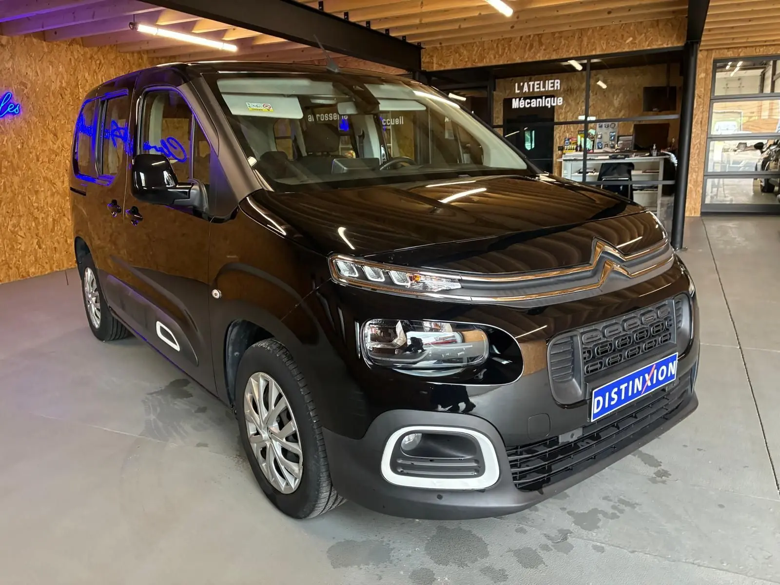 Vue 3/4 avant droit d'un Citroën Berlingo noir 2020, avec calandre distinctive et phares modernes, en intérieur d'atelier.