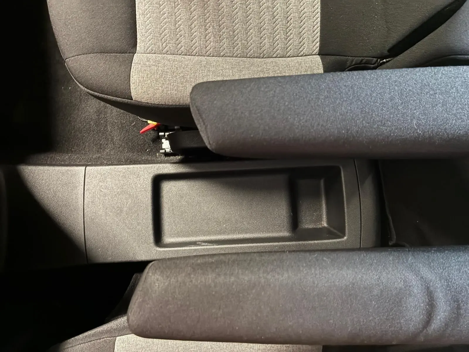 Vue plongeante sur le rangement central entre les sièges avant en tissu gris et noir du Citroën Berlingo noir 2020.